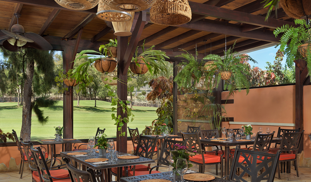 Terraza del restaurante con mesas y sillas en un campo de golf en Tenerife.