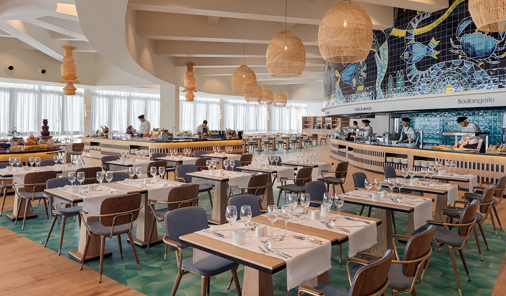 Restaurante en Tenerife con mesas preparadas y chefs trabajando en la cocina.