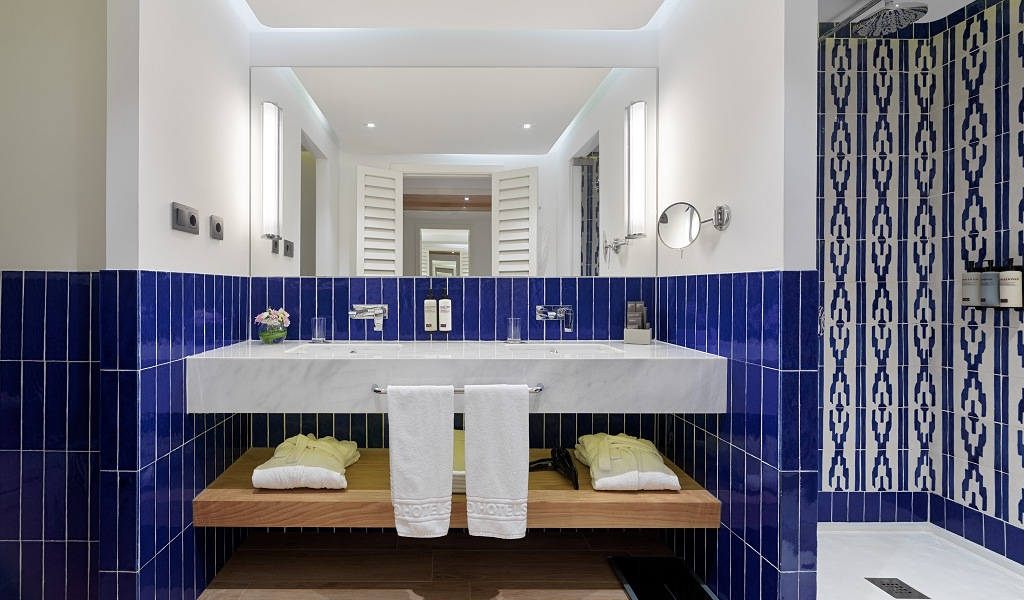 Baño moderno en hotel de Tenerife con azulejos azules y toallas en el lavabo.