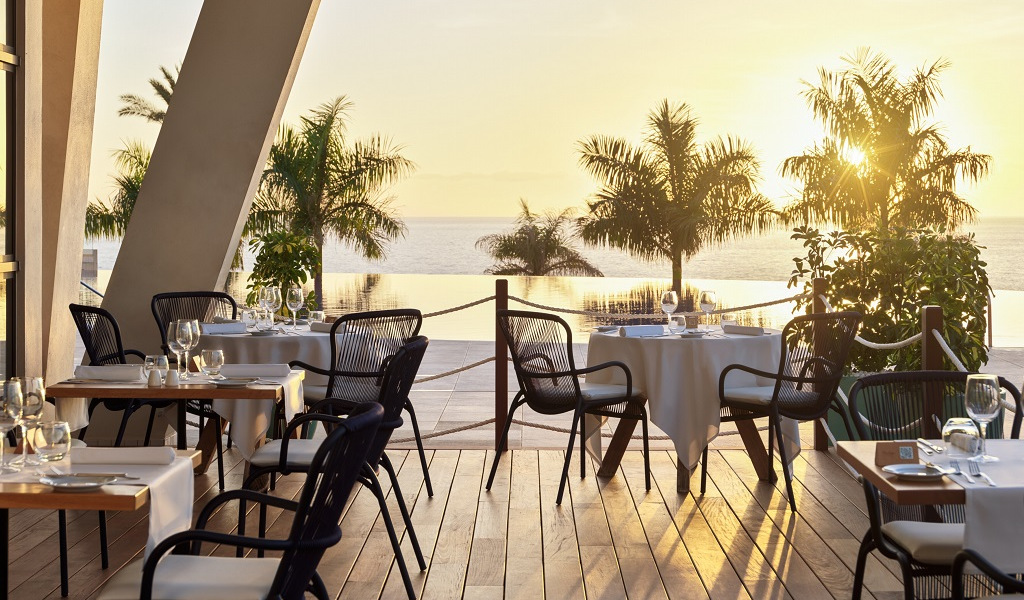 Terraza de restaurante con mesas al atardecer frente al mar en Tenerife.