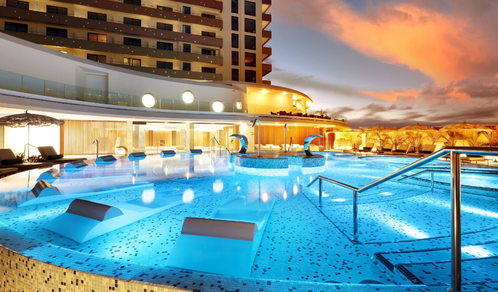 Piscina iluminada en hotel de Tenerife al atardecer.