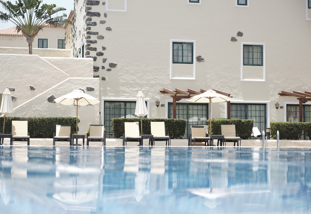 Piscina frente a un hotel con tumbonas y sombrillas en Tenerife.