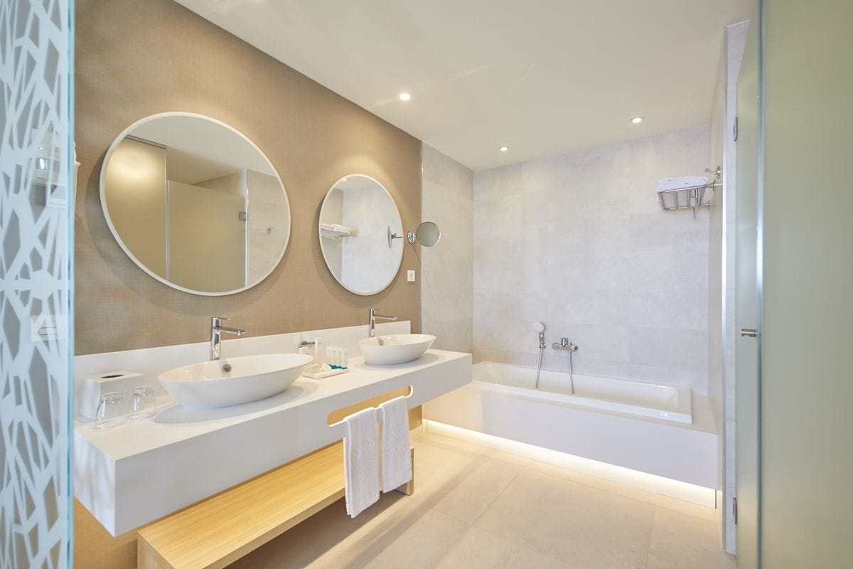Baño moderno con dos lavabos, dos espejos circulares y bañera en Tenerife.