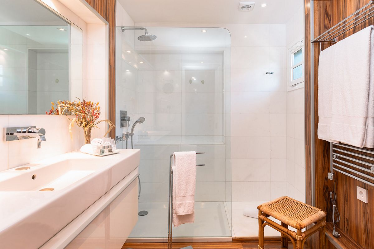 Baño moderno con ducha, lavabo blanco y toallas en un hotel de Tenerife.