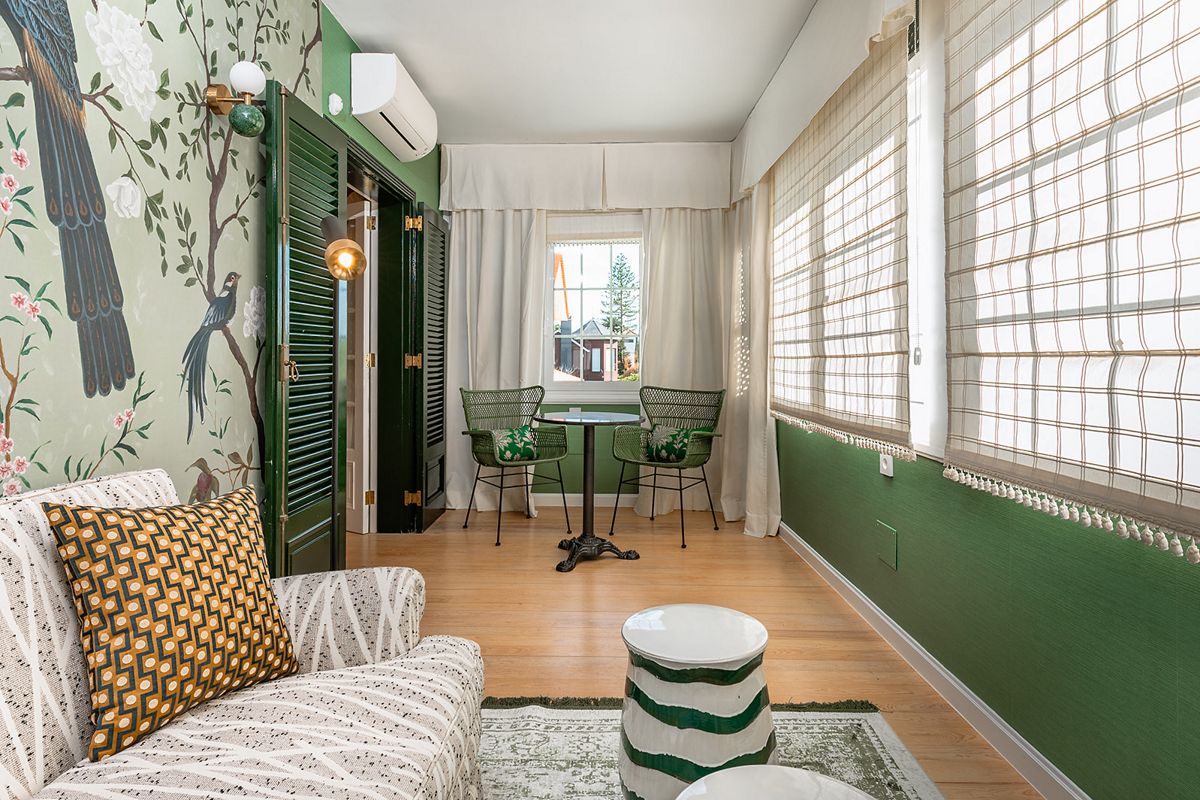 Sala de estar en Tenerife con sofá, mesa redonda y sillas verdes junto a ventana.