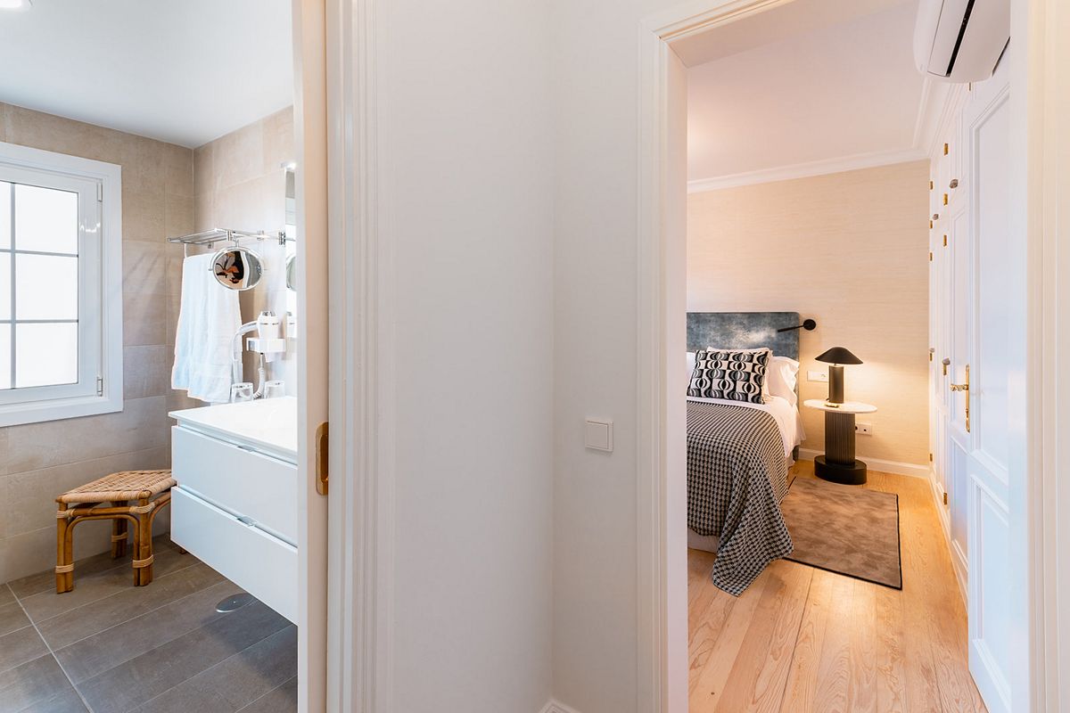 Baño con ventana, lavabo y toallas, y dormitorio con cama y lámpara en Tenerife.