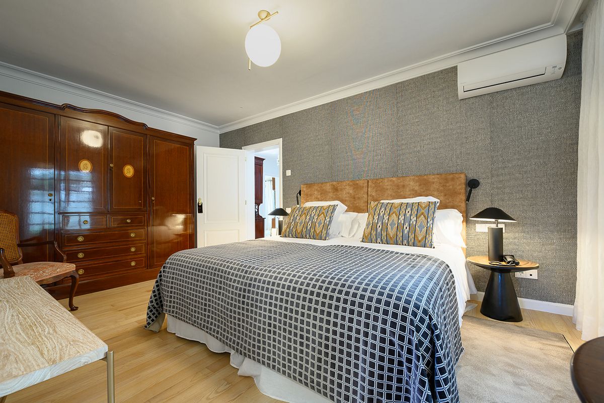 Habitación con cama matrimonial, armario de madera y lámpara de mesa en Tenerife.