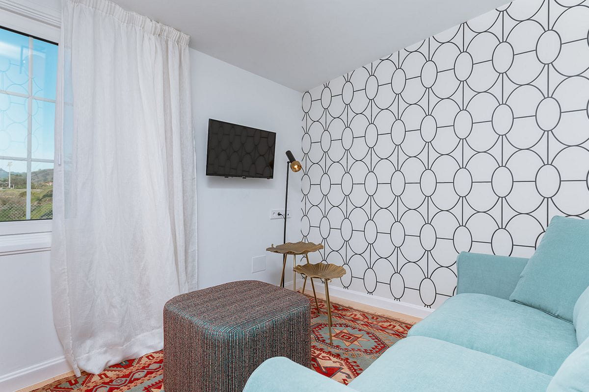 Sala de estar con sofá azul, alfombra decorativa y televisor en una casa en Tenerife.