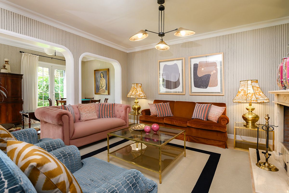 Sala de estar con sofás, mesa de cristal y cuadros colgados en una casa de Tenerife.
