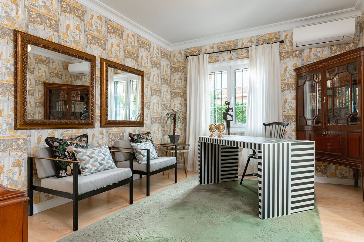 Sala de estar con escritorio rayado, sillas grises y papel tapiz decorativo en Tenerife.