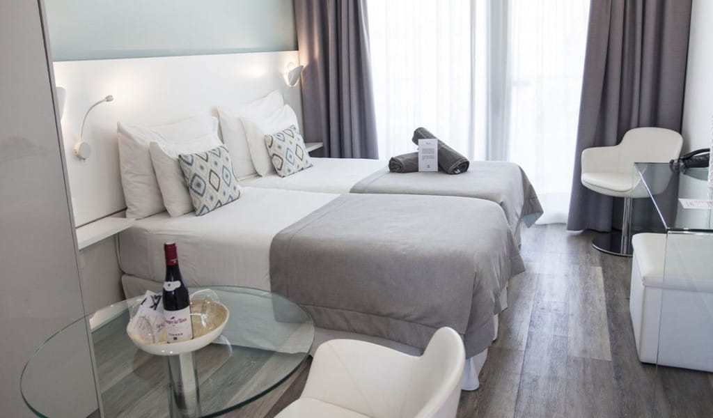 Habitación de hotel en Tenerife con dos camas individuales y botellas de vino en la mesa.