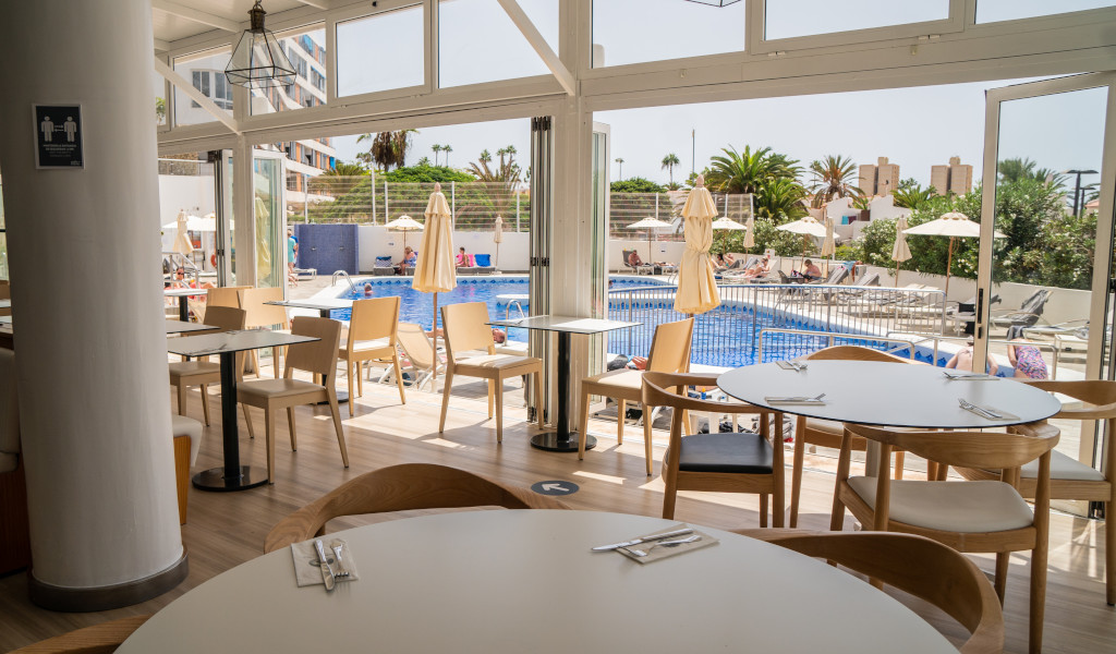 Vista desde interior de restaurante hacia piscina y terraza en Tenerife.