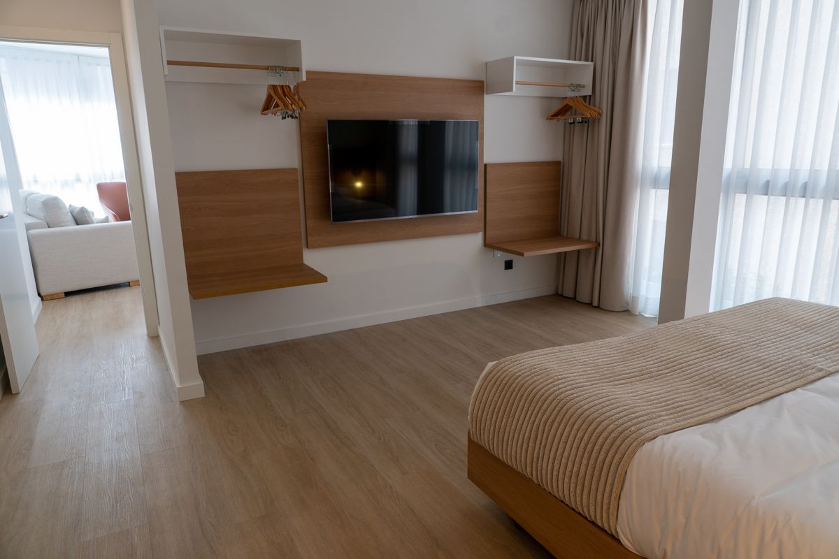 Habitación con cama, televisor, estantes y ventana grande en hotel de Tenerife.