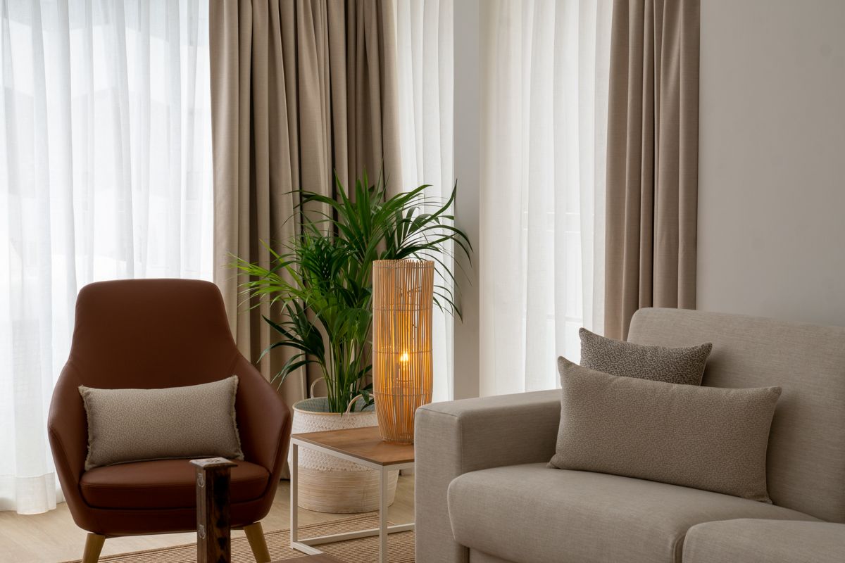 Sala de estar con sillón, sofá, lámpara encendida y planta en Tenerife.