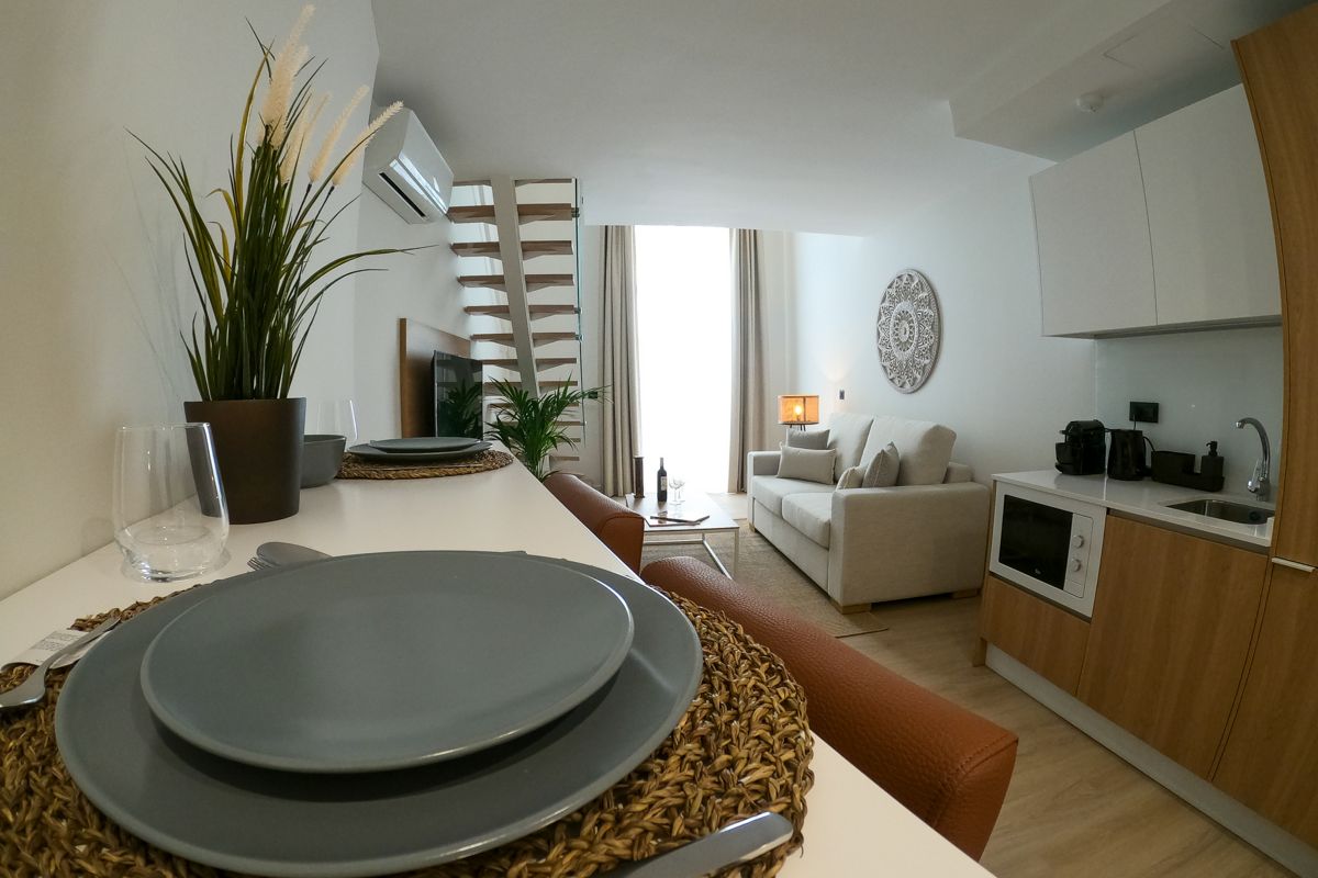 Sala de estar moderna con sofá y cocina integrada en apartamento de Tenerife.