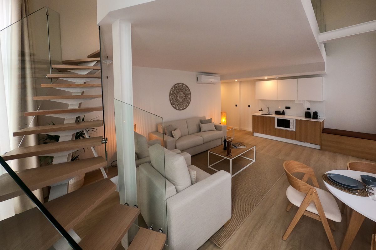 Sala moderna con escaleras de madera y cocina integrada en un apartamento de Tenerife.