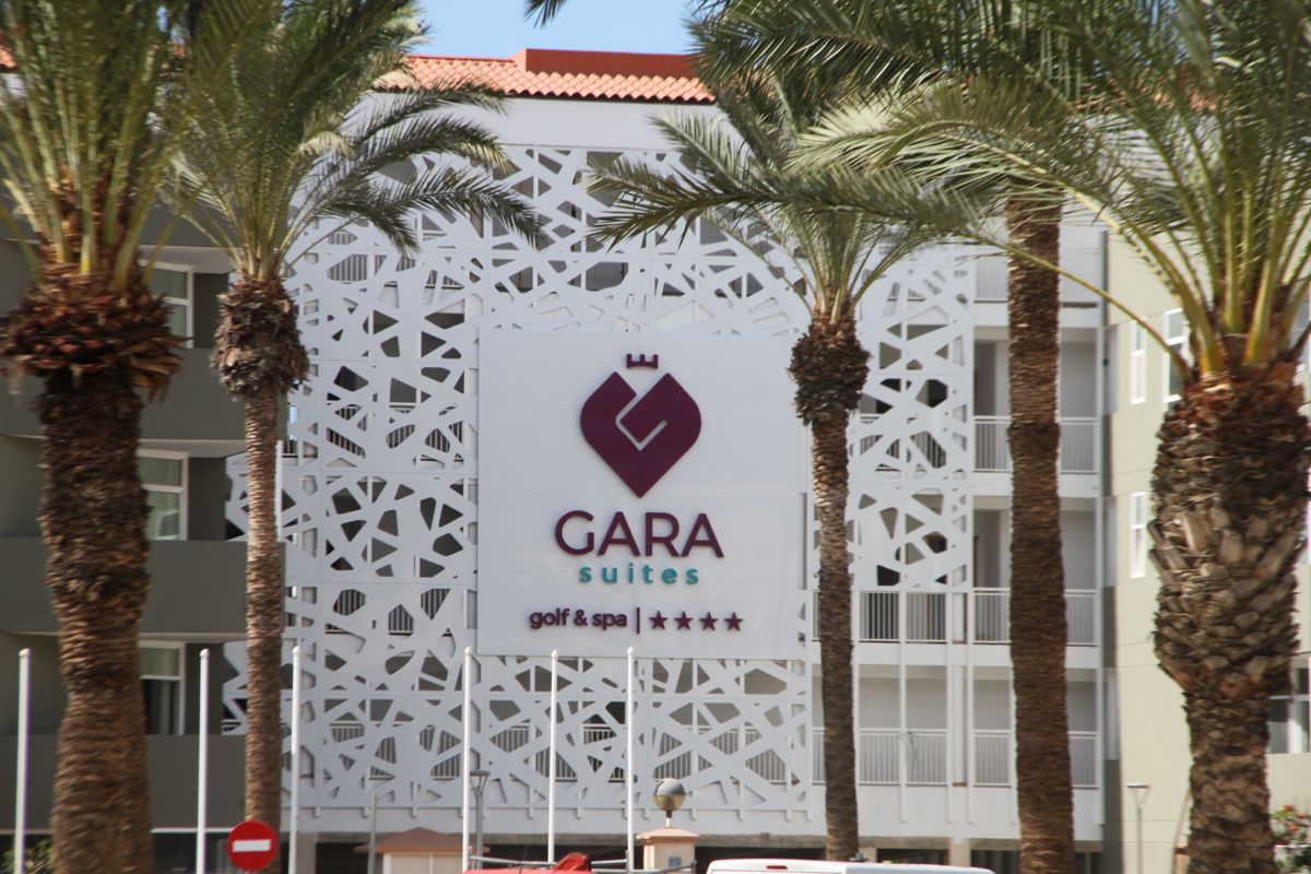 Gara Suites Golf & Spa en Tenerife con fachada decorativa y palmeras enfrente.