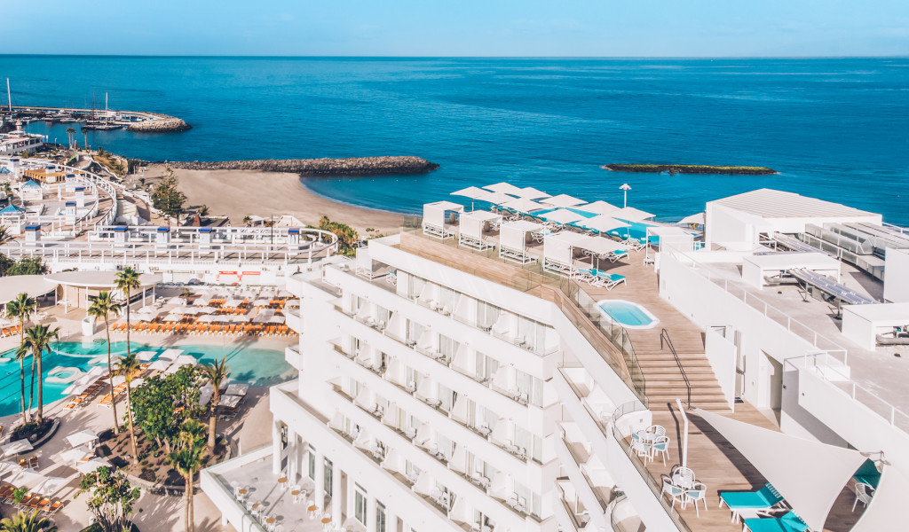 Vista aérea del hotel y playa en Tenerife con piscinas y mar azul al fondo.