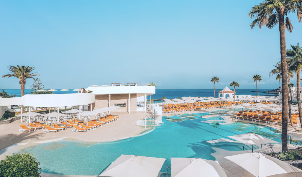 Piscina con tumbonas y sombrillas junto al mar en Costa Adeje, Tenerife.