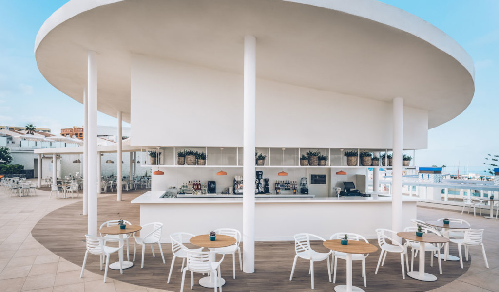 Bar al aire libre con mesas y sillas blancas en Tenerife.