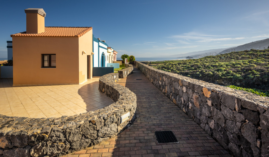 Casa junto a camino de piedra y vegetación con vistas al mar en Tenerife.