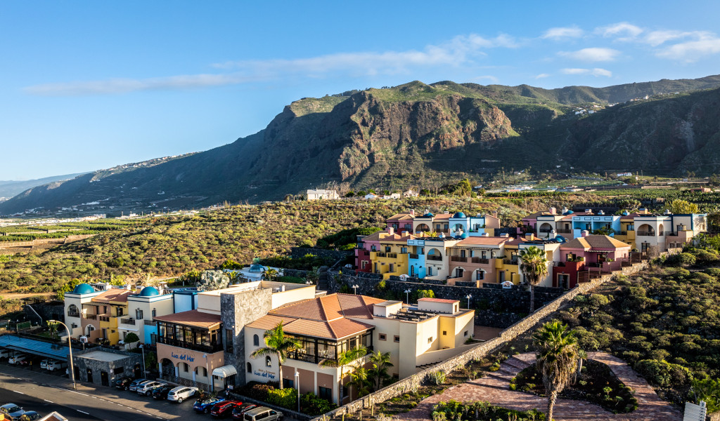 Complejo de villas coloridas en el Valle de La Orotava, Tenerife, con montañas al fondo.