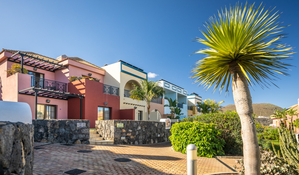Casas coloridas y vegetación en un complejo turístico de Arona, Tenerife.