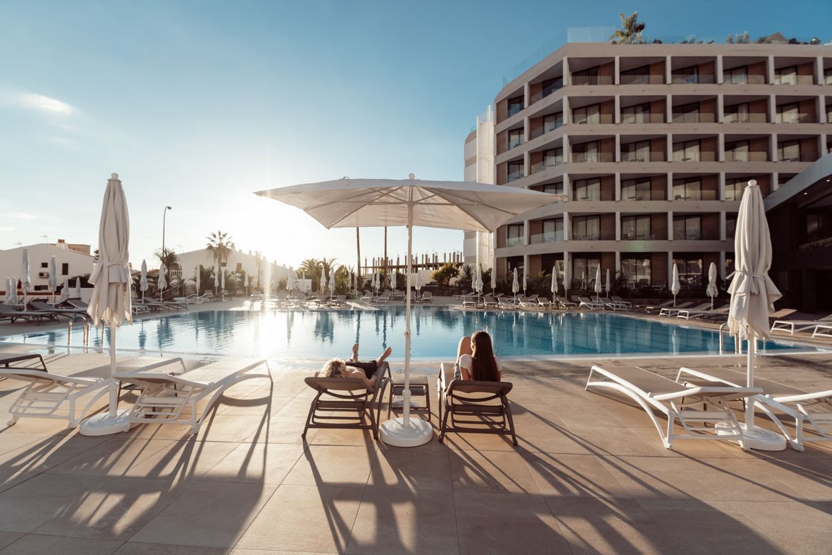 Piscina de hotel en Tenerife con tumbonas y sombrillas al atardecer.