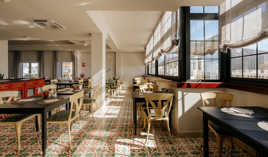 Restaurante luminoso con mesas y sillas en Adeje, Tenerife, con vista al exterior.