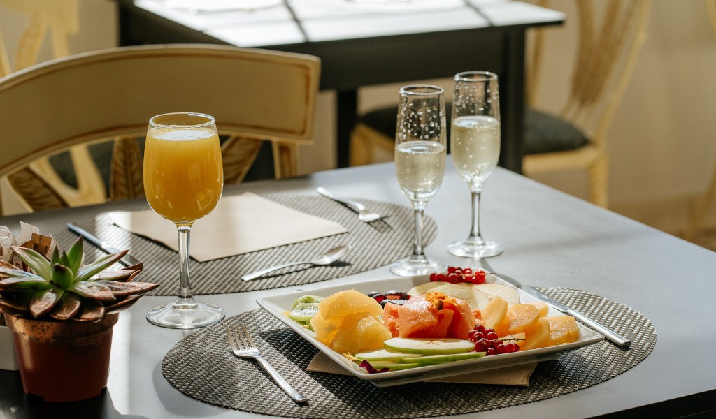 Desayuno con frutas, jugo de naranja y copas de champán en mesa en Tenerife.