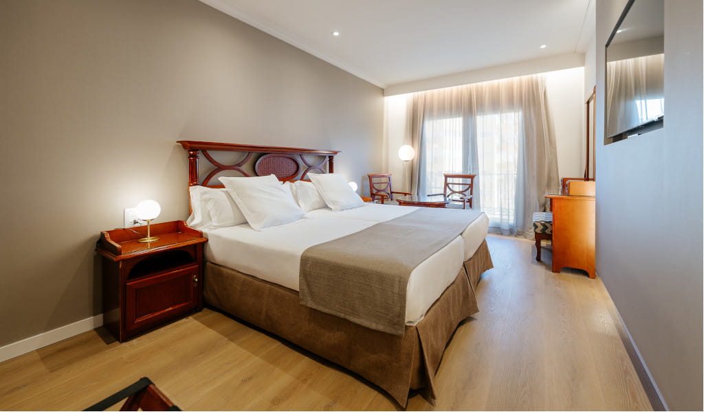 Habitación doble en hotel de Tenerife con cama y muebles de madera.