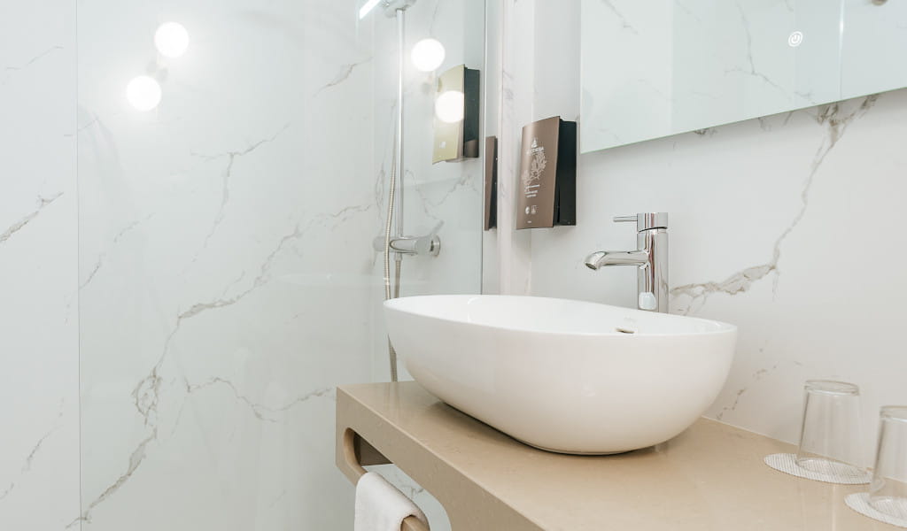 Lavabo moderno con grifo cromado y pared de mármol en baño de hotel en Tenerife.
