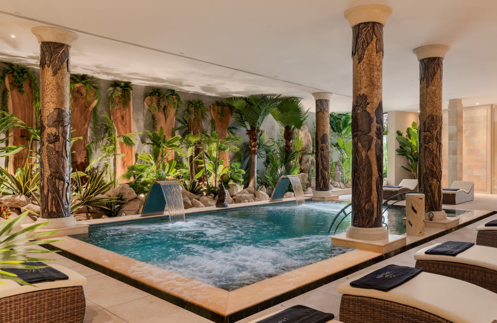 Piscina interior rodeada de columnas y vegetación en spa de Tenerife.