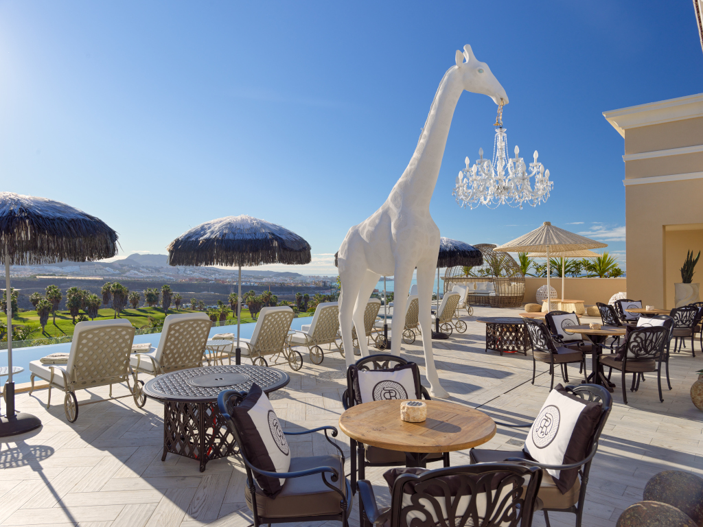 Terraza con escultura de jirafa blanca y vistas al campo en Tenerife.