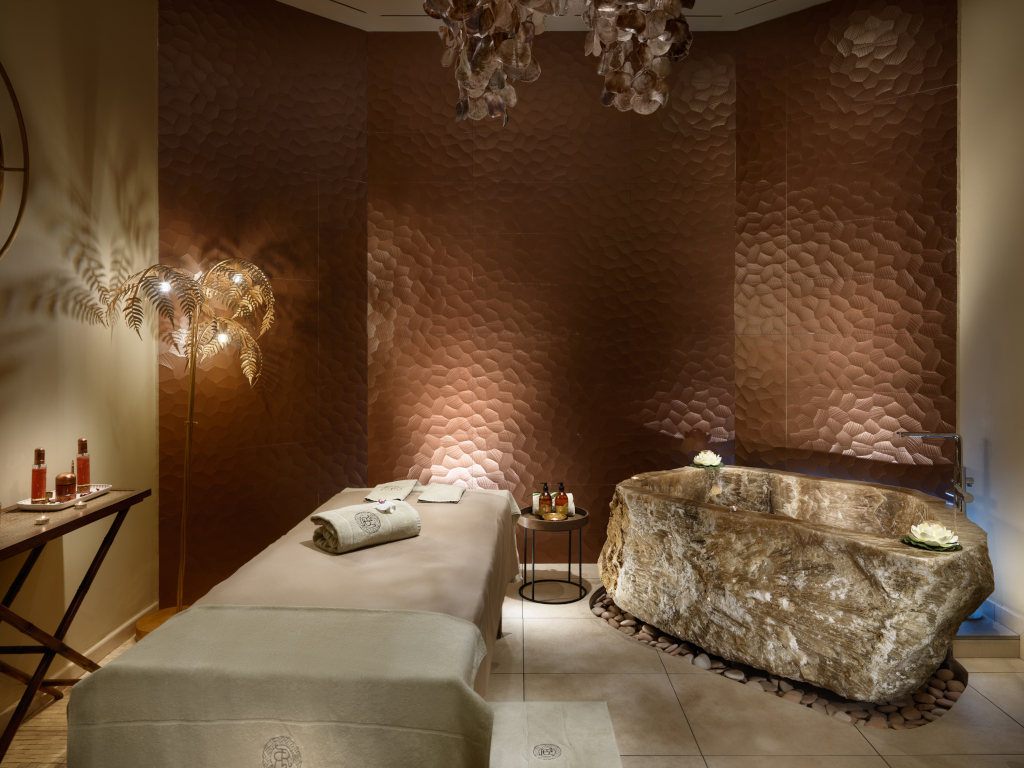 Sala de tratamiento con mesa de masajes y bañera de piedra en Tenerife.