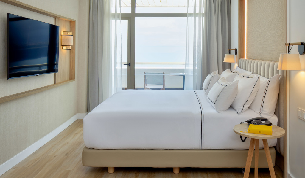 Habitación de hotel moderna con cama, televisor y vista al mar en Tenerife.