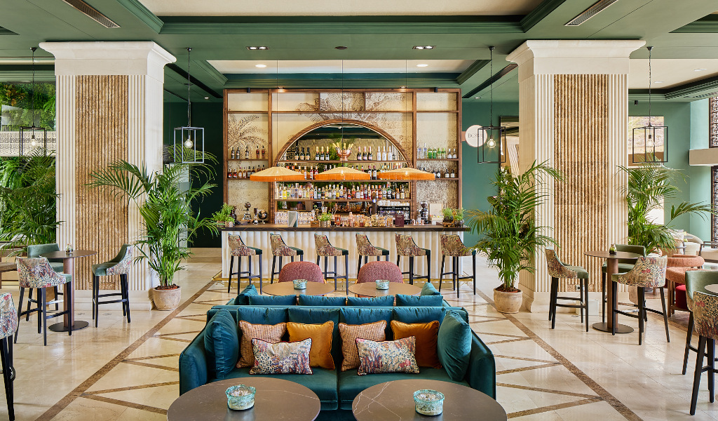 Bar elegante con sofás y sillas en un hotel de Tenerife. Botellas alineadas tras la barra.