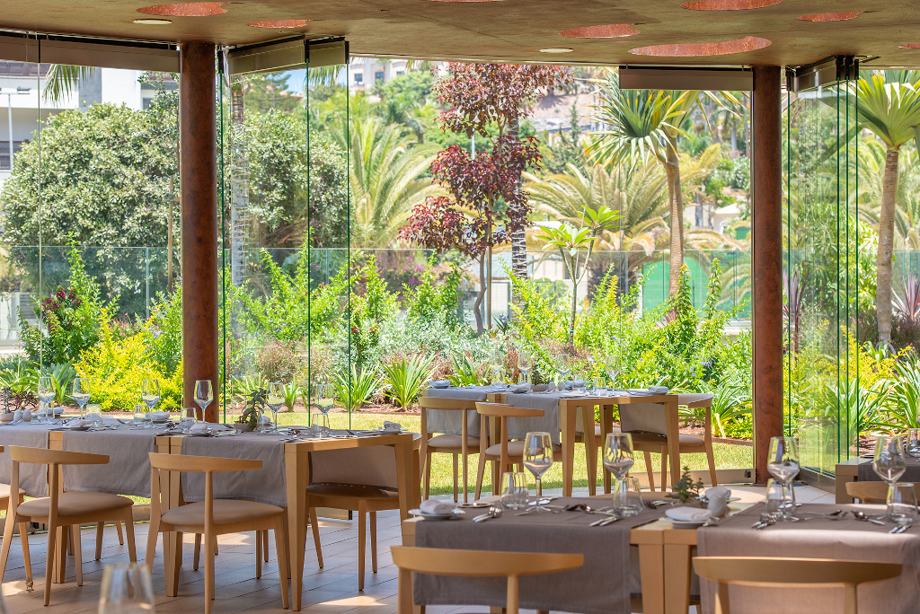 Restaurante con ventanales panorámicos y vistas a un jardín en Tenerife.