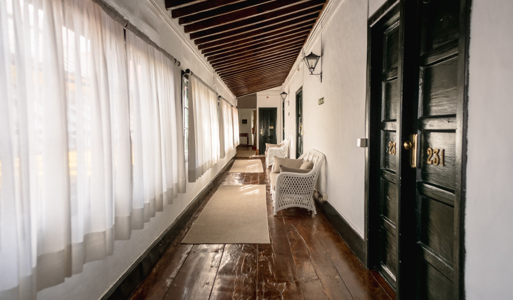 Pasillo con suelo de madera, puertas numeradas y sillas en Tenerife.