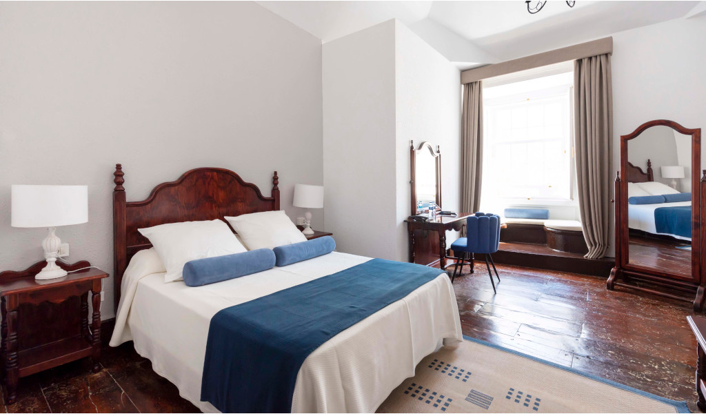 Dormitorio con cama doble, dos lámparas, espejo y ventana. Ubicación: Tenerife.