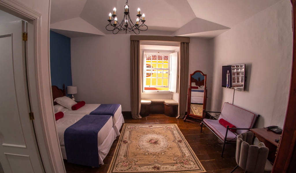 Habitación con cama doble, espejo y ventana en una casa típica de La Laguna, Tenerife.