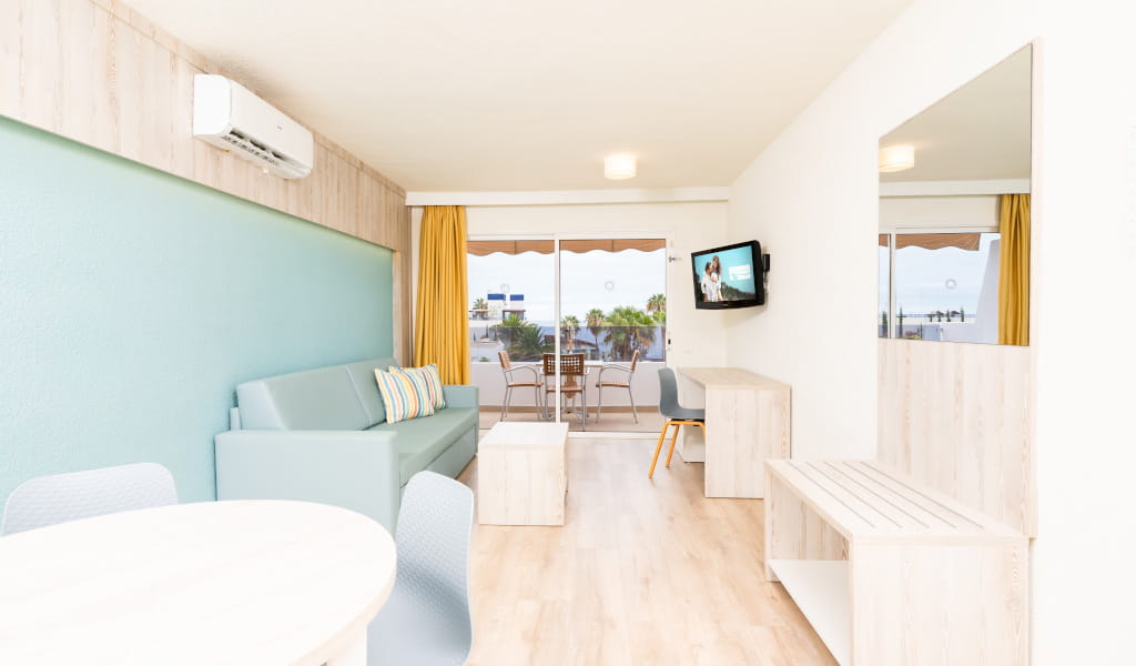 Sala de estar moderna con sofá, televisor y balcón en Santa Cruz de Tenerife.