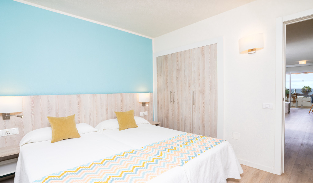 Habitación con dos camas, pared azul y salida a terraza en Tenerife.