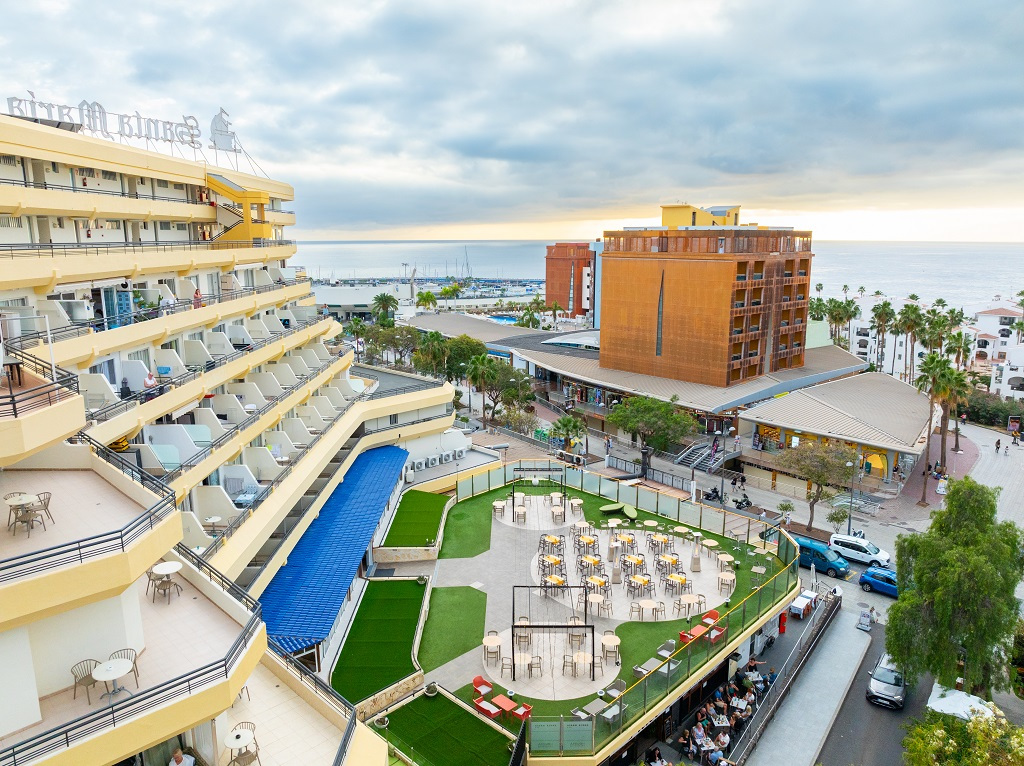 Vista panorámica de un hotel en Tenerife con el océano al fondo y terraza con mesas.