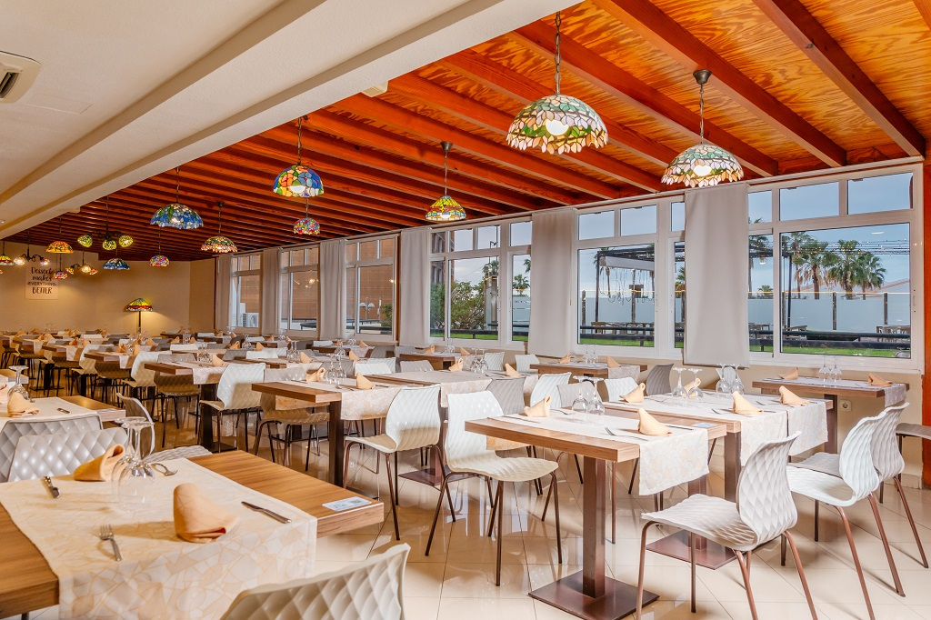 Restaurante amplio en Tenerife, mesas preparadas y vista exterior con palmeras.