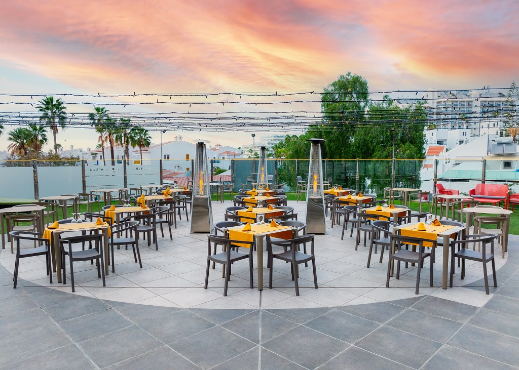 Terraza al aire libre con mesas y sillas al atardecer en Tenerife.
