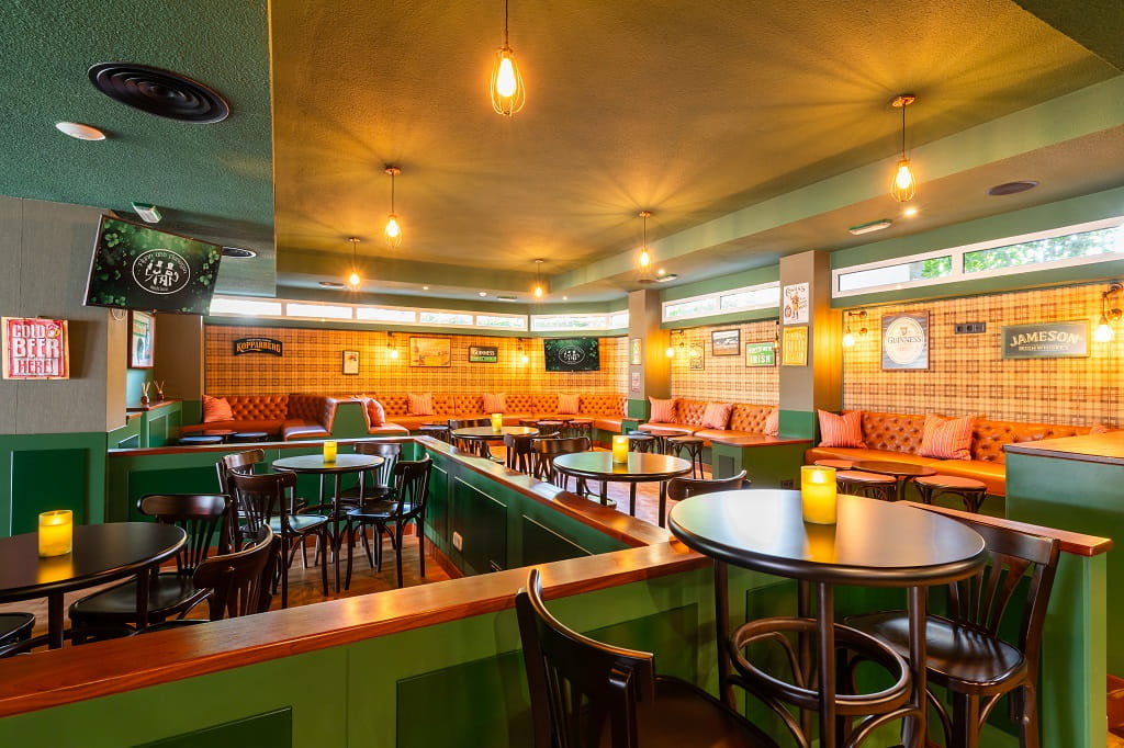Bar acogedor con mesas redondas, sillas altas y carteles decorativos en Tenerife.