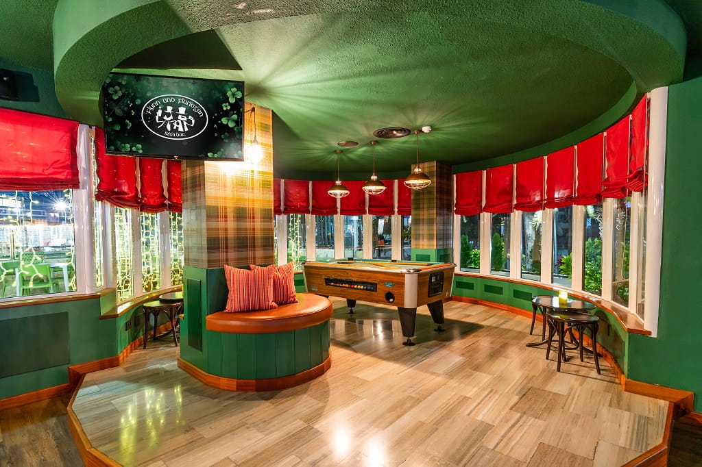 Interior de un bar en Tenerife con mesa de billar y decoración verde y roja.