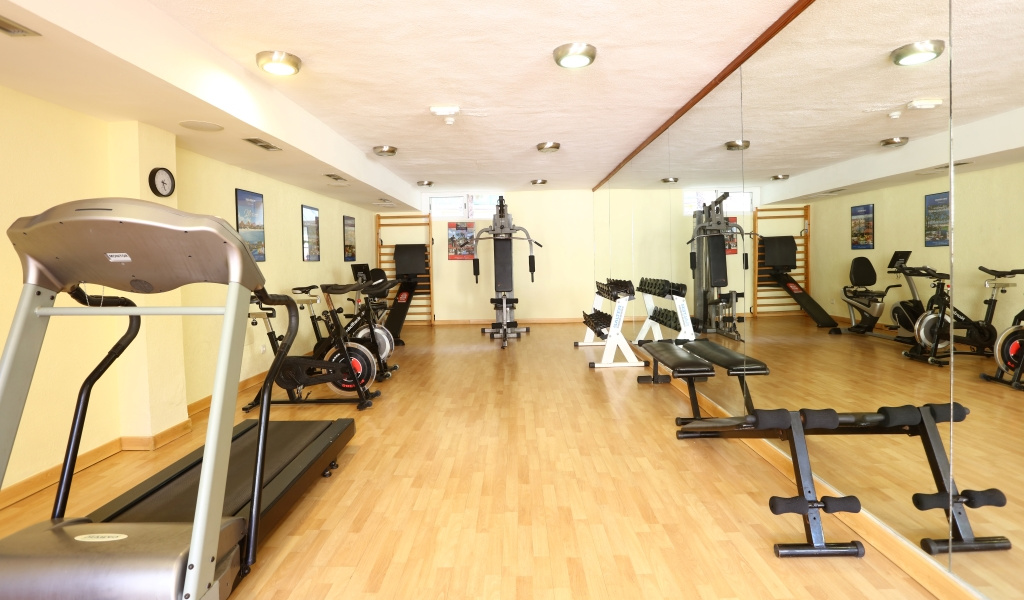 Gimnasio con equipos de ejercicio en hotel de Tenerife, incluyendo cintas y pesas.
