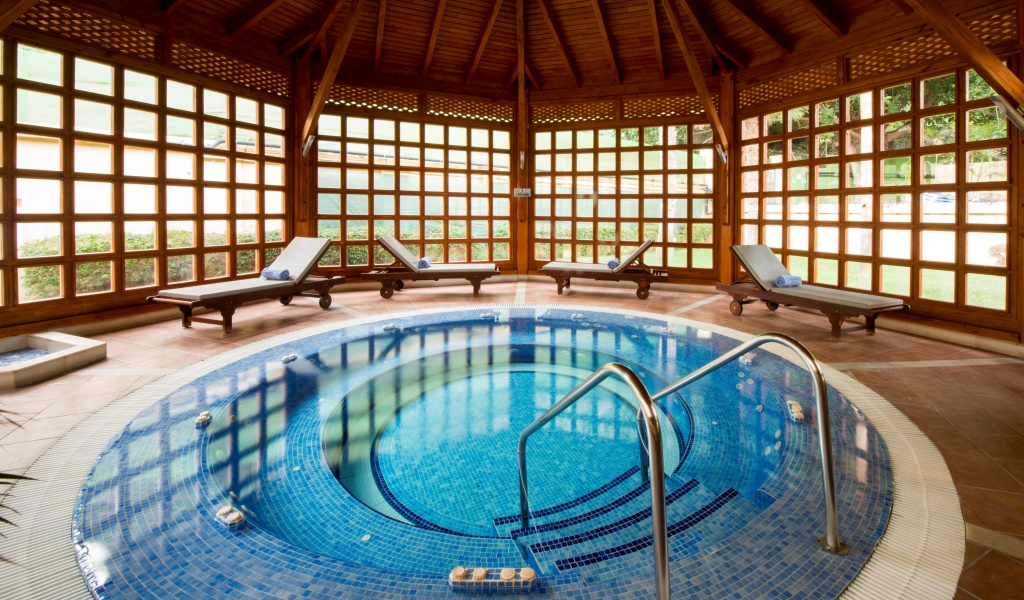 Jacuzzi cubierto rodeado de tumbonas en spa de Tenerife.